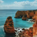 brown rock formation on sea under blue sky during daytime